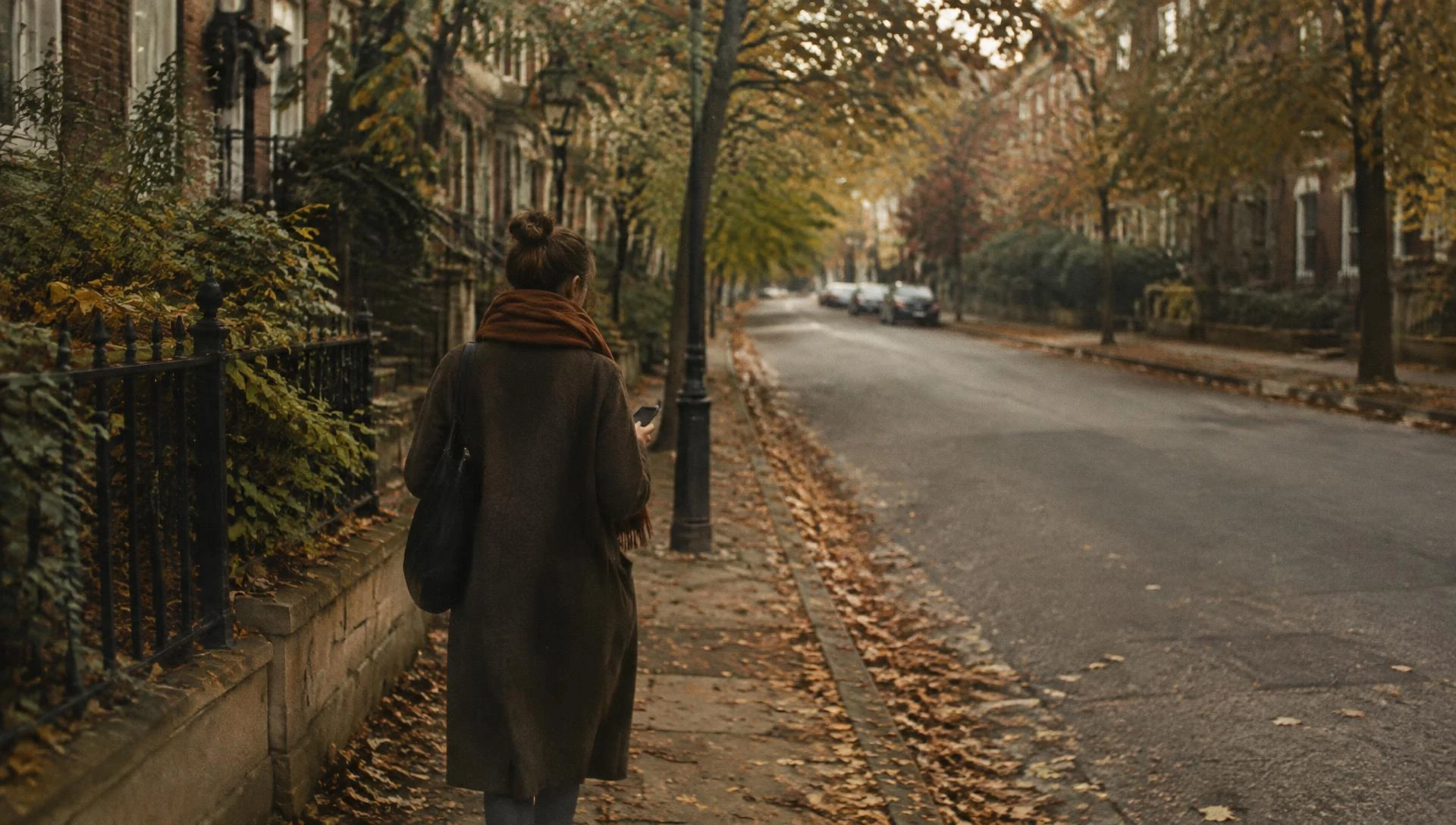 A person walking alone down a quiet tree-lined street in autumn